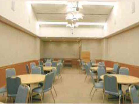 臨海斎場の火葬待合室の内観写真。9卓の円卓と54客の椅子が用意されている