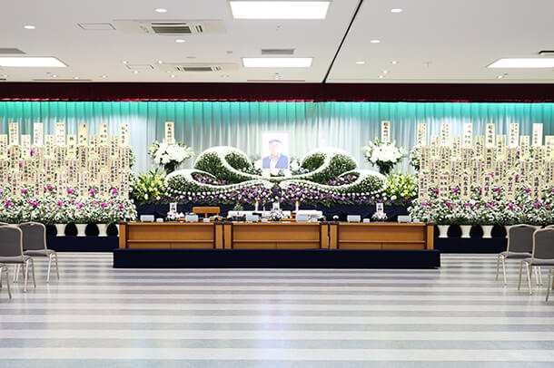 川崎市にある民営の葬儀場「平安会館さいわい」の2階葬儀場の内観。綺麗で豪華な生花祭壇が飾られている